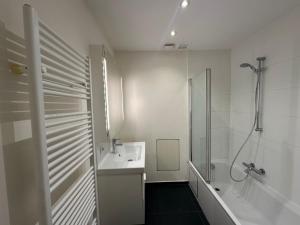 baño blanco con ducha y lavamanos en Spacious Apartment next to Port of Antwerp, en Amberes
