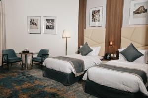 a hotel room with two beds and a table and chairs at Dream Residence Rawabi-Serviced apartments in Al Khobar