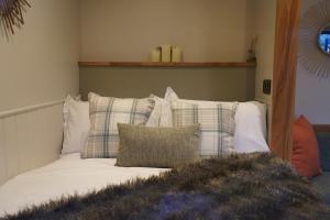 a bedroom with a bed with pillows and a mirror at The Dragonfly - Luxury Lakeside Shepherds Hut in Cotham