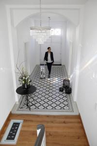 a woman walking down a hallway with a black and white floor at Kremers Freiräume in Arnsberg