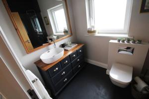 a bathroom with a sink and a toilet and a mirror at Seagrass a luxurious gem by the sea in Youghal