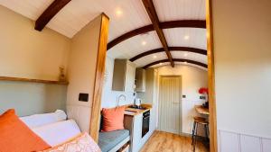 a small room with a kitchen and a living room at The Dragonfly - Luxury Lakeside Shepherds Hut in Cotham