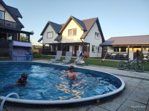 two boys swimming in a pool in a yard at Domek parterowy apartamentowy Ostoja in Rewal