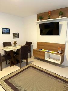 sala de estar con mesa y TV de pantalla plana en Aconchego e Conforto no Centro de Teresópolis, en Teresópolis