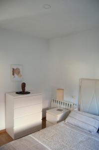 a white bedroom with a bed and a dresser at Casa en Villa Termal Las Caldas in Las Caldas