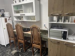 a kitchen with a table with chairs and a microwave at Casa pé na areia - Brandão House in Saco dos Cações