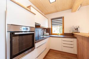 a kitchen with white cabinets and a large appliance at Apartment Drautalblick in Oberdrauburg