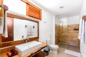 uma casa de banho com um lavatório branco e um WC. em Vila Coqueiros Boutique Hotel em Cumbuco