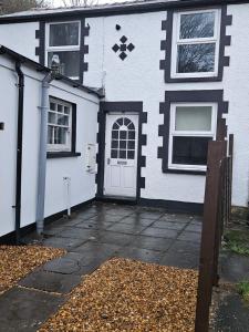 a white and black house with a door at Cwmynyscoy Cottage Pontypool NP4 5SQ in Pontypool