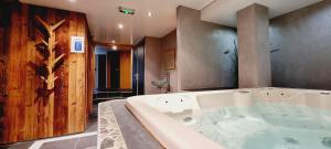 y baño con bañera y pared de madera. en Le Saint Antoine, en Les Houches