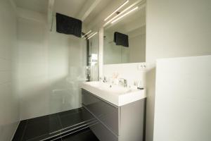 a white bathroom with a sink and a mirror at De Rietreiger in Blankenberge