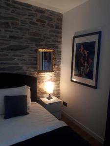 a bedroom with a bed with a lamp and a stone wall at LE SQUARE in Luchon