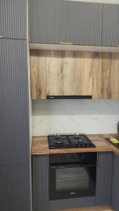 een keuken met een fornuis en houten kasten bij Квартира в отличном районе с евро ремонтом in Alma-Ata