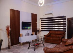 a living room with a couch and a table and a television at Peace cottage short lets and apartments in Ibadan