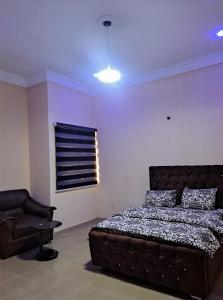 a bedroom with a bed and a chair in it at Peace cottage short lets and apartments in Ibadan