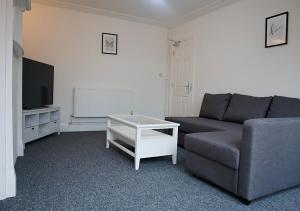 een woonkamer met een bank en een tv bij Large Capacity Comfortable Group Stay in Nottingham