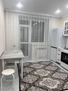 a kitchen with a table and a white refrigerator at Уютная однокомнатная квартира в центре города in Kokshetau