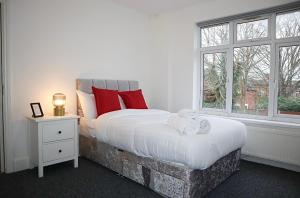 a bedroom with a large bed with red pillows and a window at Large Capacity Comfortable Group Stay in Nottingham