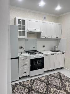 a kitchen with white cabinets and a stove top oven at Уютная однокомнатная квартира в центре города in Kokshetau