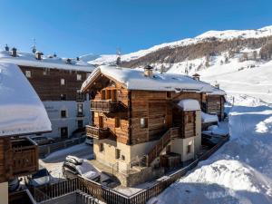 a building in the snow with snow covered mountains at Chalet Armony in Livigno