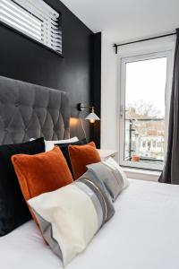 a bedroom with a bed with orange pillows and a window at Comfy & spacious Apt, 2 balconies, near the 02 arena, Greenwich in London