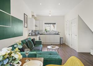 a living room with a green couch and a kitchen at 124 Vere Road in Peterborough