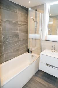 a bathroom with a shower and a tub and a sink at Comfy & spacious Apt, 2 balconies, near the 02 arena, Greenwich in London