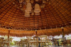 a group of tables and chairs under a straw roof at GUAJIRA CASA DEL MAR in Ríohacha