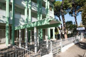 a green building with a fence in front of it at Hotel B&B Gladys in Cesenatico