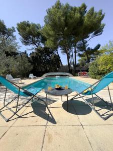 un par de sillas y una mesa junto a una piscina en Maison provençale, en Cornillon-Confoux