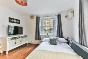 a bedroom with a bed and a tv and a window at Fantastic Central Line City-pad! in London