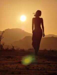 Una mujer caminando frente a la puesta de sol en Night Magic Camp, en Wadi Rum
