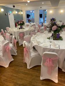ein Zimmer mit weißen Tischen und Stühlen mit rosa Bogen in der Unterkunft Hamlet Hotels Maidstone in Maidstone