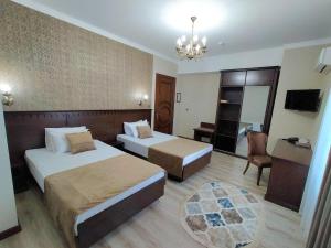 a hotel room with two beds and a chandelier at Hotel Times in Bukhara