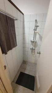 biała łazienka z prysznicem i ręcznikiem w obiekcie Kartika Lodge w mieście Bengkok