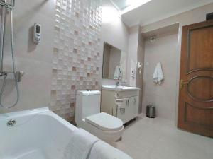 a bathroom with a toilet and a sink and a tub at Hotel Times in Bukhara