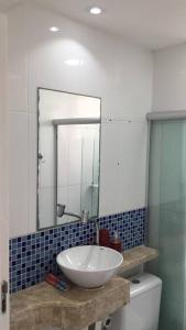 uma casa de banho com um lavatório e um espelho sobre um WC em Lindo 2/4 em Abrantes. em Lauro de Freitas