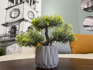 a white vase with trees in it on a table at Tirana Center Apartment - Your Cosy Corner in Tirana