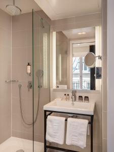 uma casa de banho com um lavatório e um chuveiro em Hotel Le Mareuil em Paris