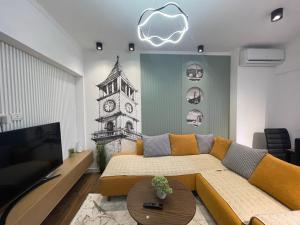 a living room with a couch and a clock on the wall at Tirana Center Apartment - Your Cosy Corner in Tirana