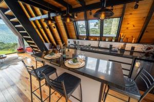 a kitchen with a large counter with chairs and tables at A Cabana mais aconchegante da Serra Catarinense in Urubici