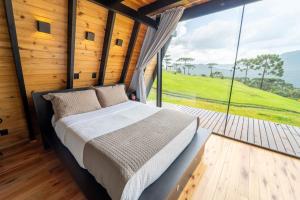 a bed in a room with a large window at A Cabana mais aconchegante da Serra Catarinense in Urubici