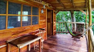 eine Veranda einer Hütte mit einer Hängematte darauf in der Unterkunft Jungle Cabins El Escondido in Muy Muy