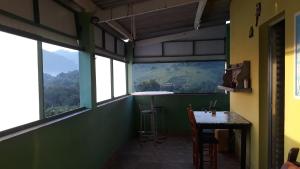 Habitación con paredes y ventanas verdes y mesa. en Recanto de cachoeiras en Itariri