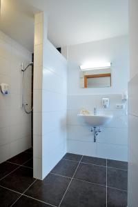 uma casa de banho branca com um lavatório e um chuveiro em Pension Schindlau em Scharnstein