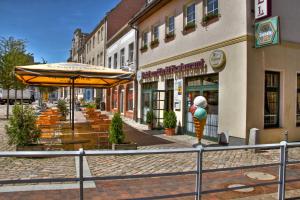 Altentreptow的住宿－Hotel am Markt Altentreptow，一条街道上,街道上摆放着桌子和遮阳伞