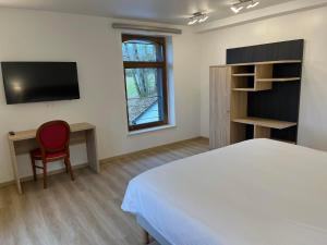um quarto com uma cama, uma secretária e uma televisão em Résidence de la Roseraie em Florenville