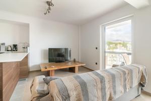 ein Schlafzimmer mit einem Bett, einem Fernseher und einem Tisch in der Unterkunft VARKIZA APARTMENT in Varkiza