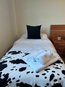 a bed with a black and white comforter with towels on it at Bicis & Vacas in La Pola de Gordón