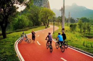 a group of people riding bikes down a road at Guilin Village Creek Inn & Free pick up service over three nights in Guilin